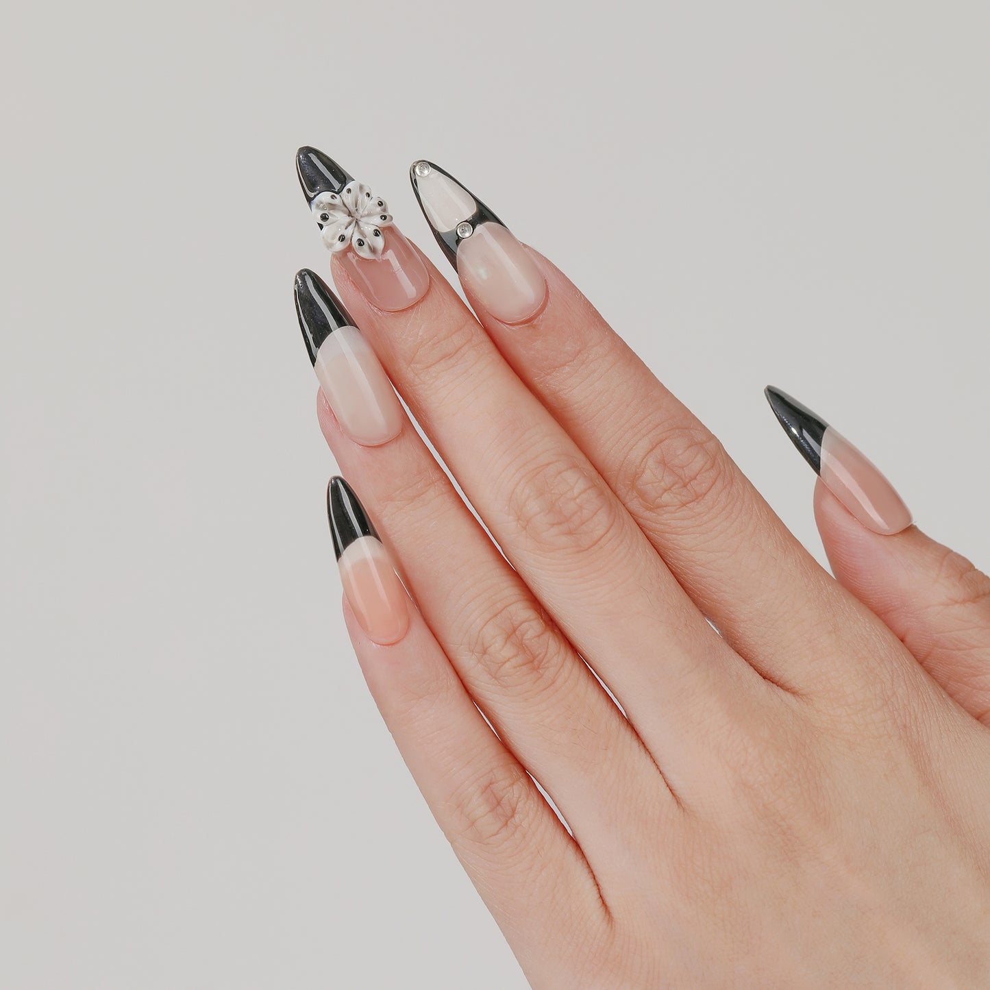 Noir Bloom long almond press-on nails worn on hand