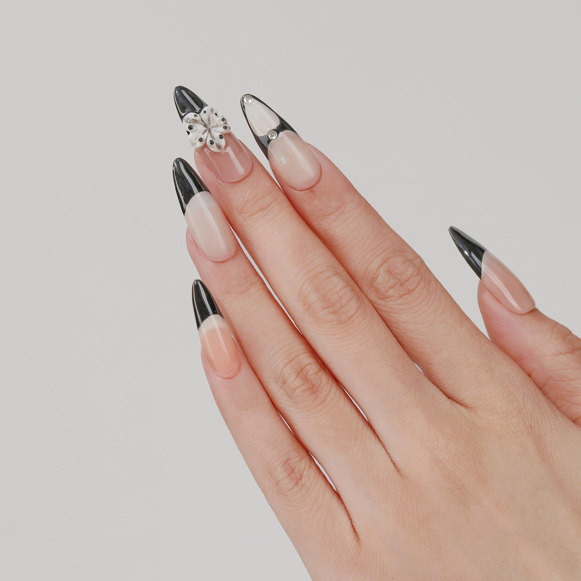 Noir Bloom long almond press-on nails worn on hand